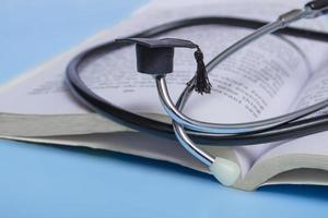 medical education. stethoscope, book and graduate hat. medical concept on blue background. graduate photo