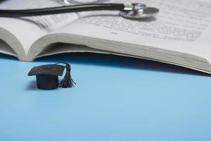 medical education. stethoscope, book and graduate hat. medical concept on blue background. graduate photo