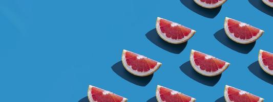 Seamless pattern of orange grapefruit with shadow on a blue background with copy space. Banner. Summer vacation minimal trendy concept. Healthy eating habits.
