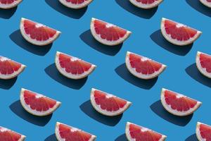 Seamless pattern of orange grapefruit with shadow on a blue background. Minimal trendy summer vacation concept. Healthy eating lifestyle.