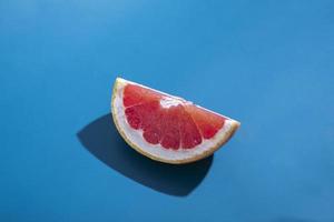 Creative concept. Sliced juicy orange grapefruit with shadow isolated on blue background. Tropical fruit minimal composition photo