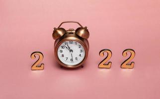 Christmas background with vintage alarm clock on pink background with numbers 2022. Close up Christmas theme. photo