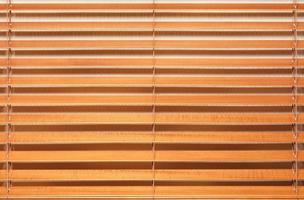 Wooden blinds with wide light brown lamellas in the interior. photo