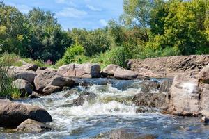 Beautiful stone rapids on the path of a small forest stream on a sunny summer day. photo