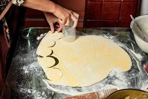 Female hands prepare dough blanks for sculpting Ukrainian dumplings. photo
