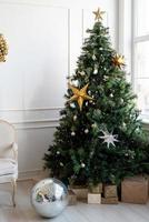 árbol de navidad con regalos y luces en la sala de estar luminosa y aireada