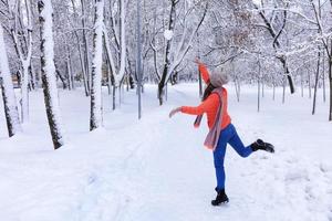 una joven y bella mujer camina en invierno por un callejón en un fabuloso parque de la ciudad cubierto de nieve. foto