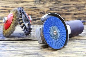 Angle grinder with grinding disc brushes lies on the background of a wooden table in a blur. photo