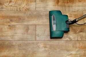 el cepillo de una aspiradora eléctrica en el fondo de un piso marrón de una tabla de piso de madera.