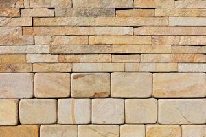 The wall is composed of hewn round stones of yellow sandstone in the lower half and rough rectangular tiles at the top. photo