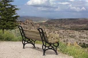 A wooden weathered bench stands against the backdrop of the mountain scenery photo
