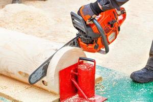 A working chainsaw in men's hands, cuts a large round log. Close-up. photo