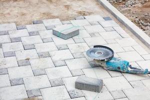 An angle grinder with a diamond cutting disc on it lies on the paving slabs against the background of the workplace, close-up, copy space. photo