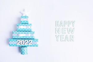 tarjeta de felicitación en blanco con árbol de navidad abstracto creativo hecho de cajas de regalo y año nuevo 2022 foto