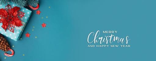 Banner de saludo de inscripción de feliz navidad con regalo de navidad plano, flor de pascua y estrellas foto