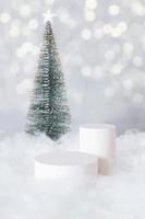 Podio o pedestal mok-up para cosméticos en la nieve con un árbol de Navidad en formato vertical de fondo bokeh