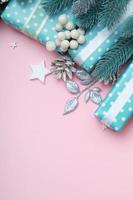 Christmas greeting card with blue gifts, berries and pine flat lay on pink background with copy space vertical format photo