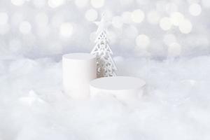 Podios mok-up para cosméticos en la nieve con un árbol de Navidad sobre fondo bokeh foto