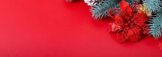 Banner de navidad con poinsettia y ramas de pino sobre fondo rojo con espacio de copia foto