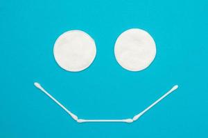 Hisopos sanitarios higiénicos y bastoncillos de algodón en forma de un icono de sonrisa sobre fondo azul.