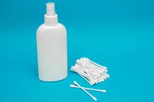 Cotton buds and plastic bottle on blue background photo