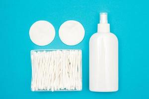 Cotton pads, plastic bottle and cotton buds on blue background photo
