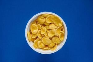 Cornflakes in white bowl on blue background photo