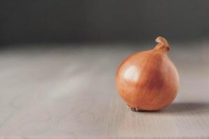 Onions on white wooden table on gray background photo