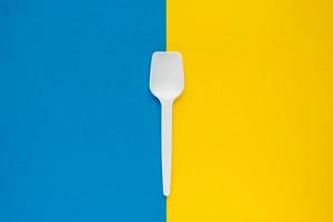 White plastic spoon on blue and yellow background photo