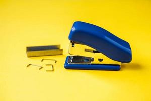 Blue stapler with metal staples on yellow background photo