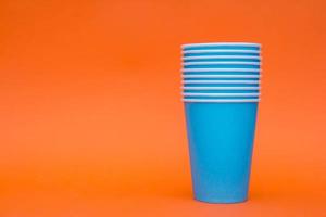 Many blue paper cups on orange background photo