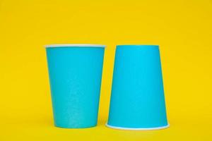 dos vasos de papel azul sobre fondo amarillo foto