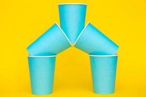 Pyramid of blue paper disposable cups on yellow background photo