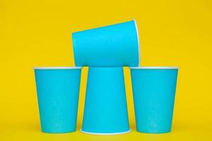 Pyramid of blue paper disposable cups on yellow background photo
