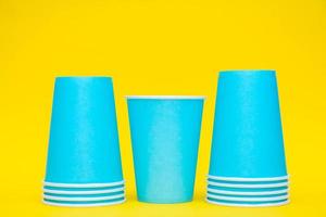 Colocación de vasos de papel azul en una línea sobre fondo amarillo