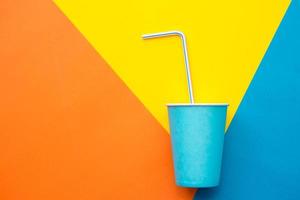 Vasos de papel azul con pajitas de plástico de colores para beber sobre un hermoso fondo multicolor foto