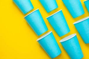 Pattern from blue paper disposable cups on yellow background photo