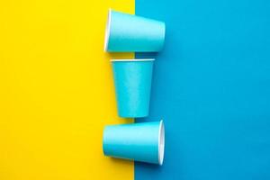 vasos desechables de papel azul fondo amarillo y azul foto