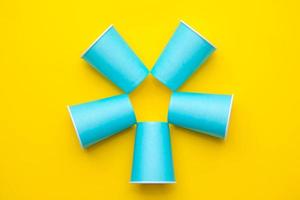 patrón de vasos desechables de papel azul sobre fondo amarillo. listo para la fiesta
