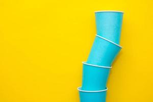 Blue paper disposable cups on yellow background photo