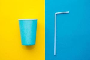 Vasos de papel azul con pajitas de plástico de colores para beber fondo amarillo y azul
