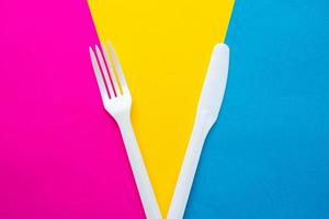 Tenedor y cuchillo de plástico blanco sobre fondo multicolor foto