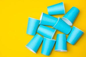 Muchos vasos desechables de papel azul sobre fondo amarillo