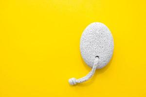 Natural pumice stone with white rope on yellow background