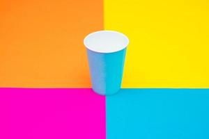Vaso desechable de papel azul sobre un hermoso fondo multicolor foto