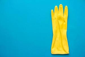 Guante de goma amarillo para limpiar colgar sobre fondo azul. foto