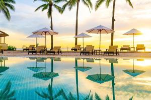 sombrilla y silla alrededor de la piscina en el hotel resort con amanecer en la mañana foto