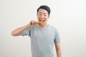 young Asian man with fried chicken on hand photo