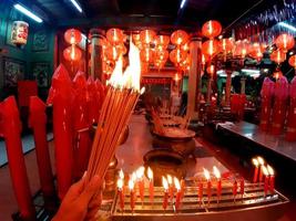 Quema de incienso en el santuario deseando buena suerte, en un santuario con velas, linternas rojas, cultura asiática