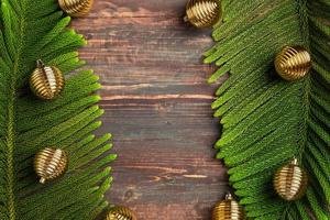 Hoja de pino de navidad con adornos dorados sobre mesa de madera